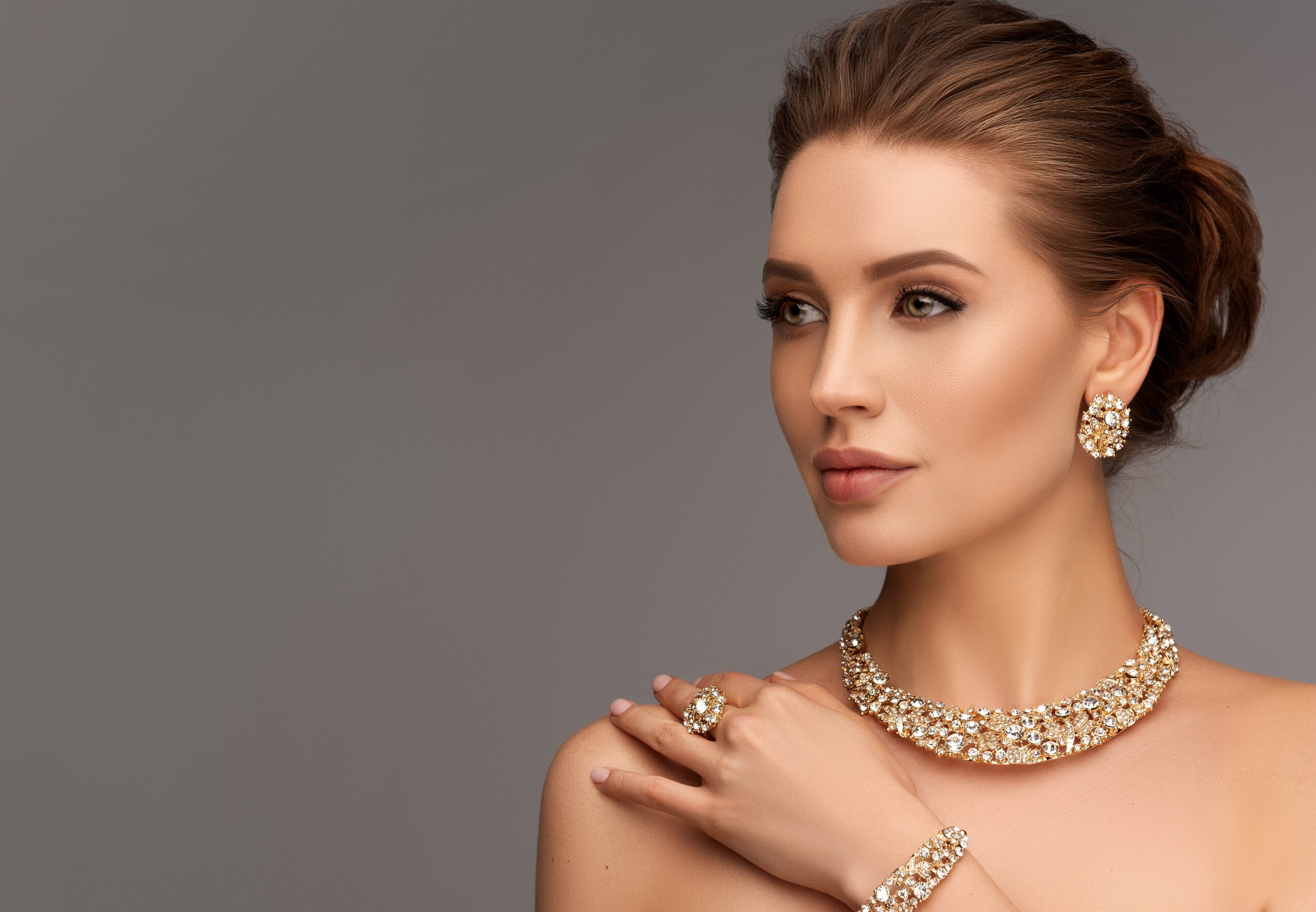 Gold layered necklaces and statement earrings worn by a model, showcasing minimalist jewelry trends