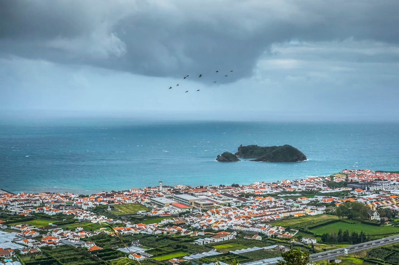 Scenic view of lush green hills and volcanic craters in the Azores, Portugal, surrounded by the Atlantic Ocean.